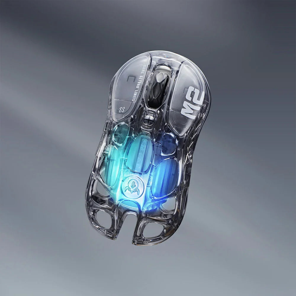 GravaStar Mercury M2 Transparent Black gaming mouse, a 2024 Red Dot Award-winning design featuring a sleek transparent black finish with ambidextrous ergonomic shape, compatible with palm, tip, and claw grips. Equipped with the high-precision PAW3395 sensor (26,000 DPI, 650 IPS acceleration, 1,000 Hz wireless polling rate) for pixel-perfect tracking, plus 82 hours of battery life (USB-C wired/Bluetooth 5.1). Highlighted specs: 5 programmable buttons with macro support, 5 customizable RGB lighting modes (16.